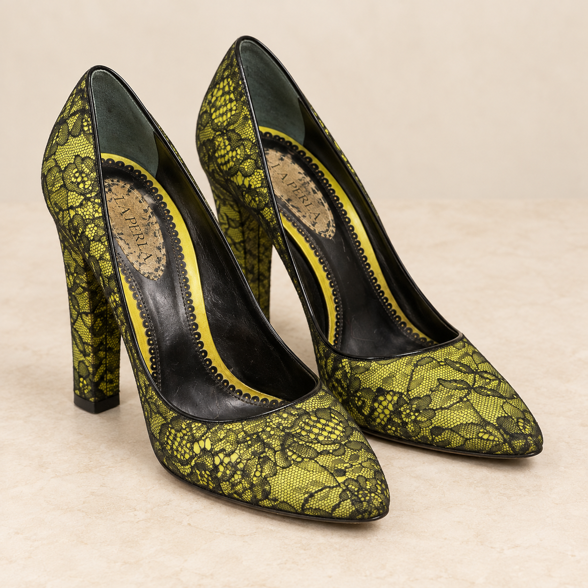 AI-enhanced studio-style presentation of La Perla pointed-toe pumps in chartreuse and black floral lace; see original item photos for exact condition